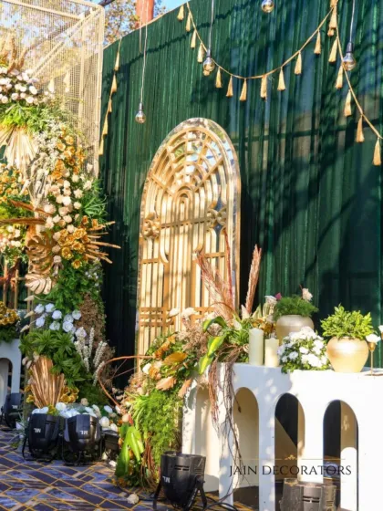 A detail shot of a rustic-chic decor corner. The combination of a mirrored arch, pampas grass, and a textured green wall creates a sophisticated and modern look.