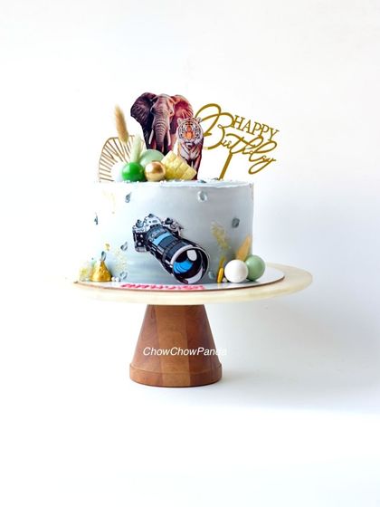 A special cake for a wildlife photographer. This pineapple cake is decorated with a camera topper and edible images of a tiger and elephant.
