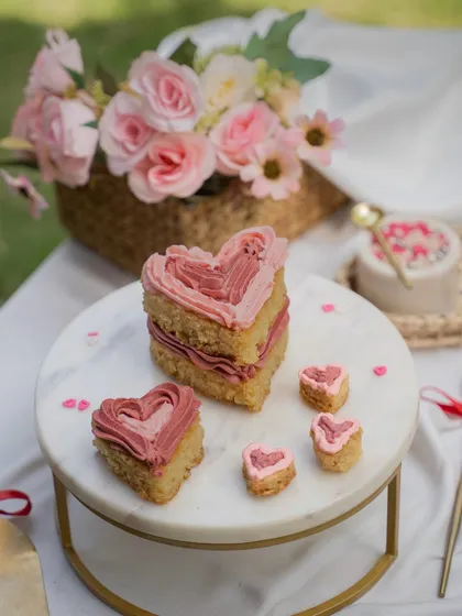 A deconstructed heart-shaped cake for a Valentine's Day shoot. This artistic shot, set on a marble stand, creates a soft and romantic mood perfect for a bakery's seasonal menu.