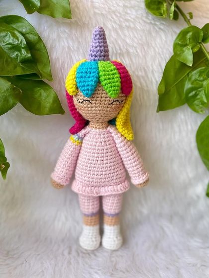 A magical unicorn doll with rainbow hair and a sparkly horn. She is dressed in a cozy pink outfit and is ready for enchanting adventures.