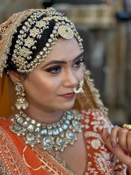A close up portrait showcasing the beautiful, sharp eye makeup and the intricate details of the traditional Rajasthani jewelry. The look is both powerful and elegant.