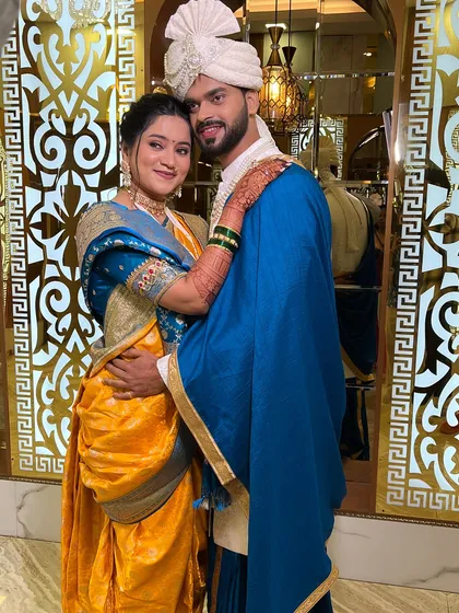 A classic couple portrait. The bride's makeup is flawless, complementing her yellow and blue saree and the groom's attire.