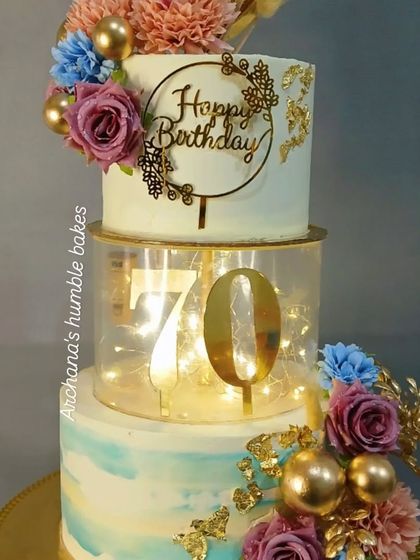 A stunning 70th birthday spacer cake. The middle tier is lit up with fairy lights and features the number 70 in gold.