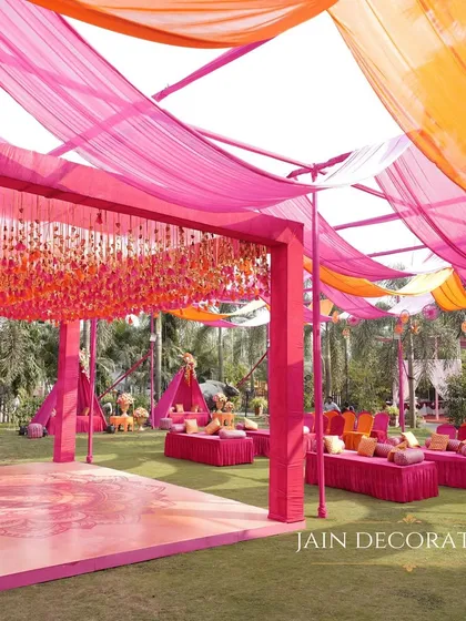A wide shot of the vibrant outdoor Mehndi setup. The flowing drapes create a beautiful canopy over the entire lawn, with a central dance floor and lounge areas for a full day of celebration.