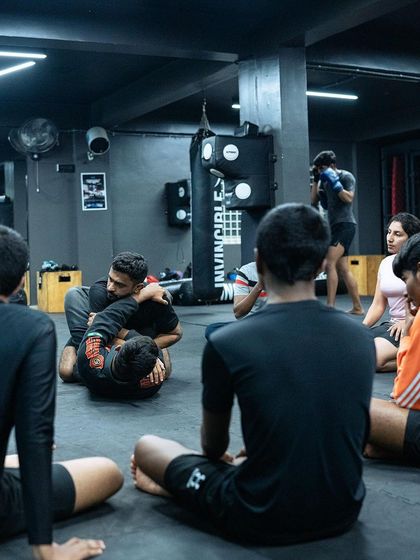 I demonstrate a grappling technique to a circle of students. This focused instruction ensures everyone understands the details of the move before they practice it.
