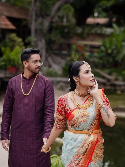 A couple walks hand-in-hand by the pond, the serene water and greenery creating a peaceful and romantic setting.