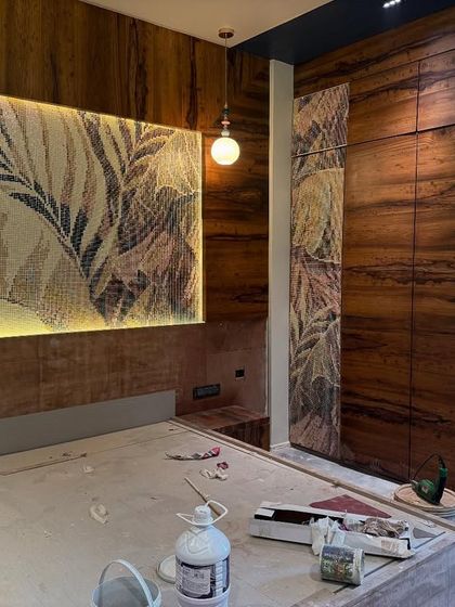 A beautiful mosaic tile panel depicting tropical leaves serves as a stunning headboard feature. This work-in-progress shot shows how we integrate artistic elements directly into the architecture of the room.