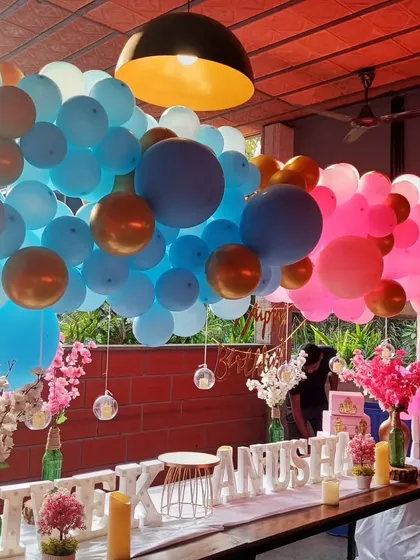A closer view of the gender reveal balloon installation. The mix of blue, pink, and metallic gold balloons creates a full and festive look over the main party table.
