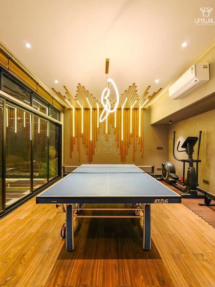 Who says your rooftop room can't be a game room? This interior features a table tennis table, a home gym setup, and unique decorative lighting, all with a view of the outdoors.