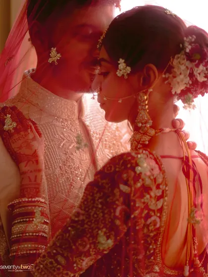 A moment of pure poetry. The bride and groom are captured through her red veil, a soft, intimate portrait that speaks of love and tradition.