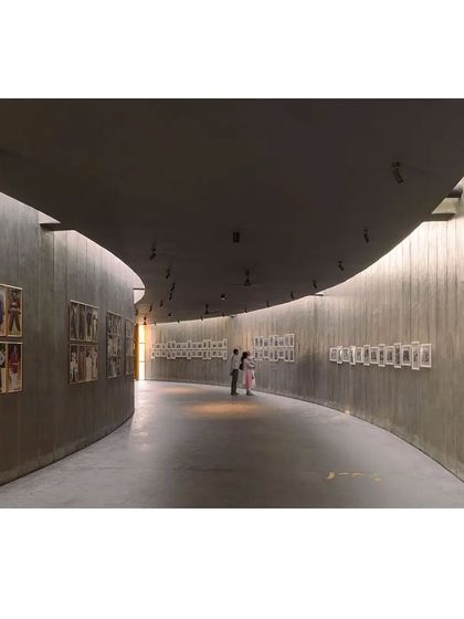 Another view of the curved gallery, showing how the space encourages a slow, meandering pace. The lighting is designed to be soft and indirect, focusing attention on the exhibits.