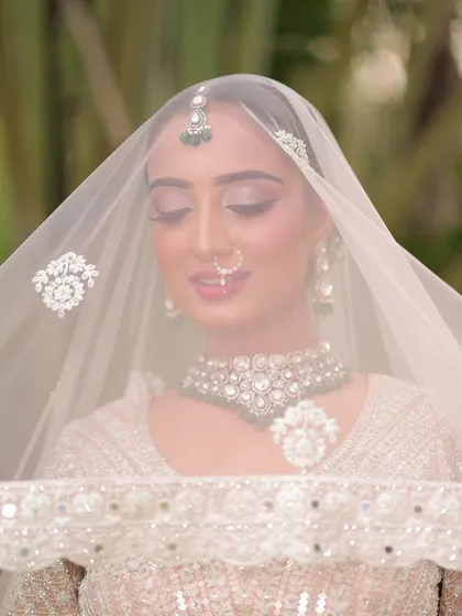 A dreamy shot through the veil. The soft-focus effect highlights the delicate eye makeup and the bride's serene expression.