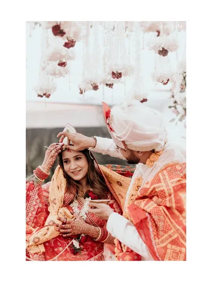 The Sindoor Daan, a pivotal moment in a Hindu wedding. The groom applies sindoor to his bride's hair parting, symbolizing their union. I capture this with a focus on the tenderness and significance of the gesture.