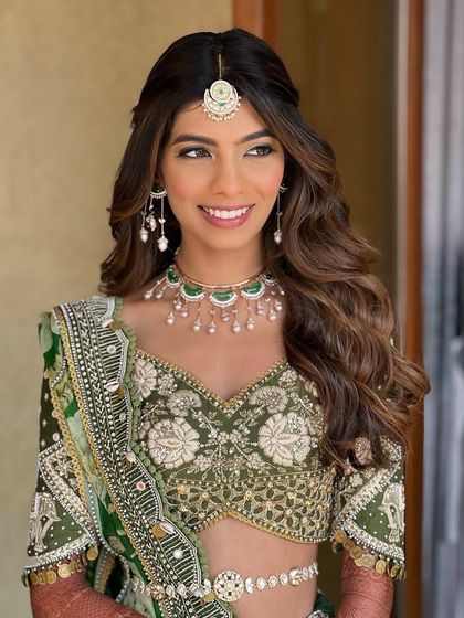 A beautiful, smiling portrait. The makeup is kept soft and radiant, with a focus on enhancing her natural features and creating a luminous glow.