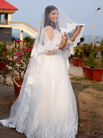 A full shot of the woman in the white gown with a beautiful lace-trimmed veil.