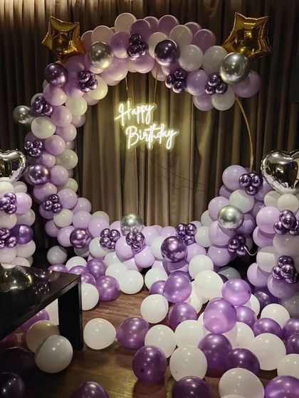 A beautiful purple and white balloon arch for a birthday. The mix of chrome purple, pastel purple, and white balloons, along with star and heart foils, creates an elegant and celebratory feel.