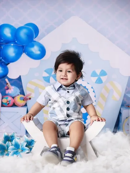 This little boy is all smiles in our blue candy-themed first birthday setup. The detailed backdrop and props create a complete and immersive scene for his special photos.