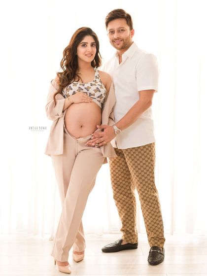 A stylish and modern maternity portrait. The couple's fashionable attire and confident pose create a chic and memorable image.