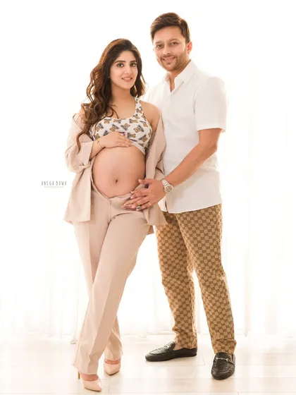 A stylish and happy couple's portrait. Their coordinated modern outfits and genuine smiles make for a fresh and contemporary maternity photo.