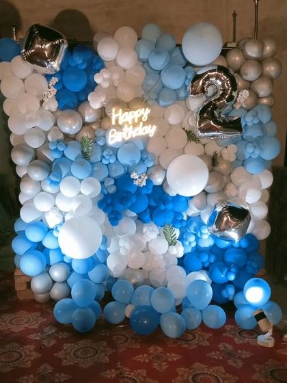 A full wall of blue and white balloons for a 2nd birthday, with a neon sign.