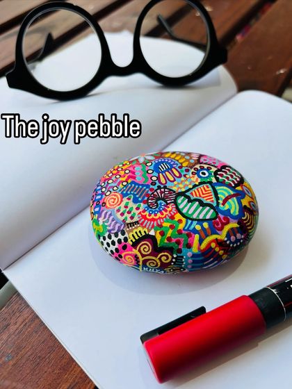 I call this one 'The joy pebble'. This hand-painted paperweight is a celebration of spontaneity and color therapy, perfect for brightening up your workspace.