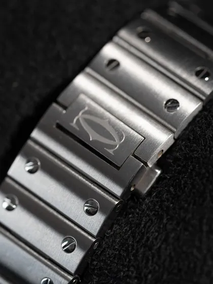 The integrated steel bracelet of the Santos, showing the engraved Cartier logo on the clasp. The design with its signature screws is as famous as the watch itself.