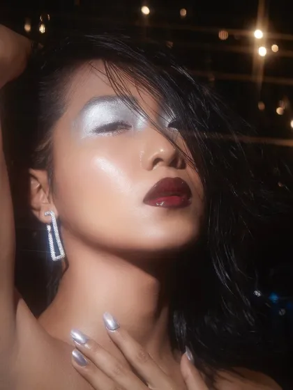 A glamorous look from a student's second portfolio shoot, featuring a silver metallic eye and a glossy dark lip under dramatic lighting.