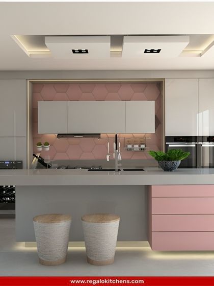 A playful yet sophisticated design, this kitchen combines soft pink and grey cabinetry with a hexagonal tile backsplash. The island provides a clean workspace and casual seating, with under-cabinet lighting adding a warm glow.