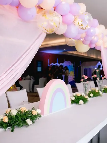 A close-up of the guest table setup, showing the custom rainbow centerpiece and floral arrangements.