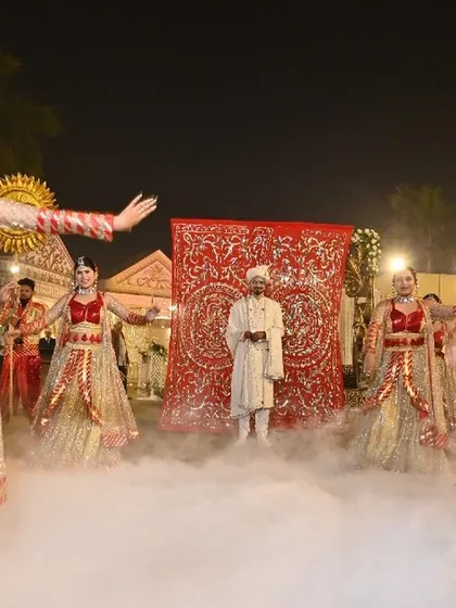 A grand and mesmerizing groom entry, where dancers create a beautiful formation around the groom. The use of smoke and traditional props like the sun motifs enhances the royal theme.