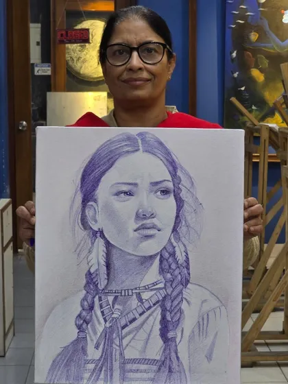 A proud student holds up her finished ballpoint pen portrait, a beautiful and expressive piece of art.