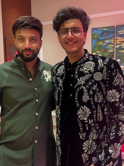 Another view of the custom black velvet sherwani with detailed white and silver floral embroidery, designed for a celebrity client's wedding.