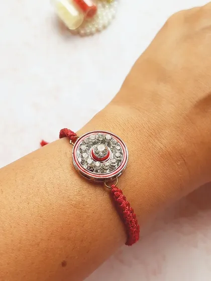 This sparkling Rakhi is perfect for adding a bit of glam to the traditional ceremony. The center is filled with crystals and it's tied with a classic red braided thread.