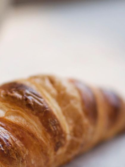 A close-up view reveals the intricate, honeycomb-like structure inside our croissants. This airy interior is the hallmark of a properly proofed and baked pastry, something we take great pride in.