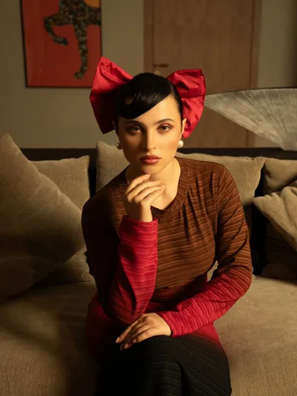 A quirky and high-fashion portrait featuring a large red bow. This image adds a playful and memorable element to the brand's campaign, showcasing a more editorial side.