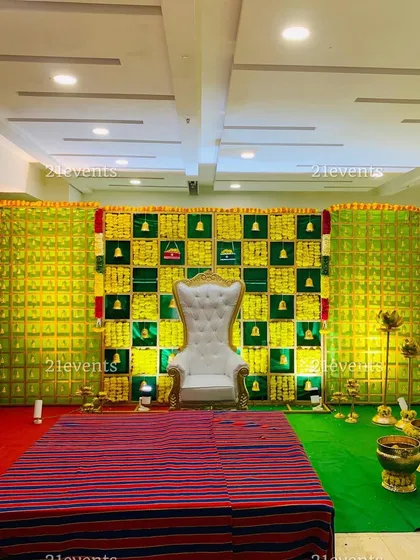 A wide view of a traditional backdrop made with betel leaves and marigolds, featuring hanging bells. This versatile design is perfect for engagements, naming ceremonies, or baby showers.