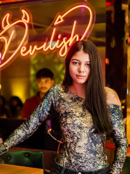 A guest posing in front of the neon 'Devilish' sign. The decor at the venues I play adds to the overall party experience.