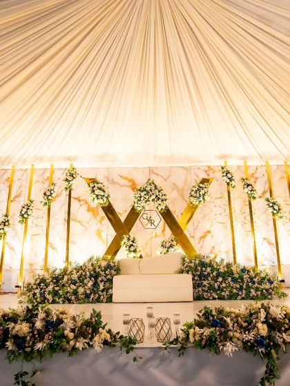 A full view of the stunning reception stage. The draped ceiling, marble and gold backdrop, and lush floral arrangements all came together to create a breathtaking setting for Rijo and Gigi's celebration.