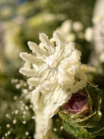A close-up of a delicate, handcrafted flower detail from a floral arrangement.