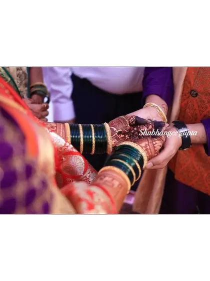 A candid moment from a wedding ceremony, capturing the beauty of the bride's henna stain. The rich color is a key part of the traditional bridal look.
