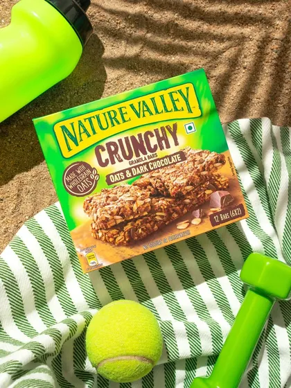 We created a beach scene in our studio using sand, a striped towel, and fitness props to showcase this granola bar as the perfect on the go snack. The harsh lighting mimics bright sunlight, creating strong shadows and a summery feel.