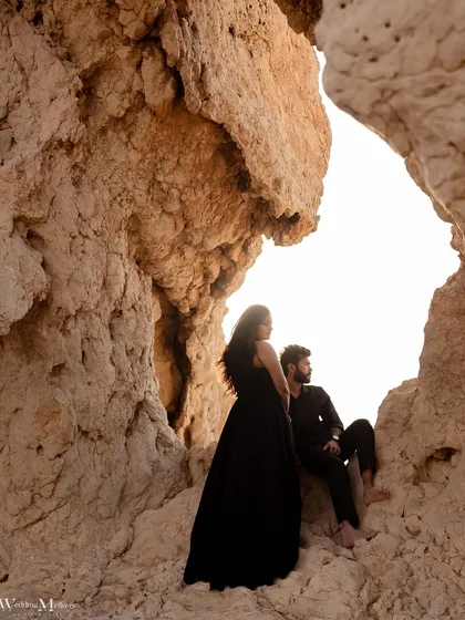 A beautifully framed shot of the couple inside a rock cave in Dubai. The natural arch creates a unique frame, highlighting them against the bright sky for a creative elopement portrait.