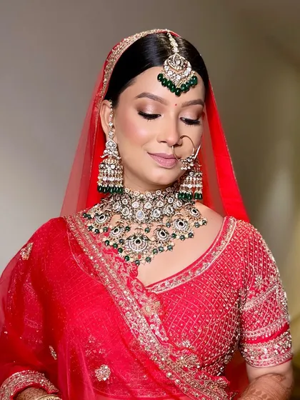 Another angle of this elegant bridal look. The soft, neutral makeup allows the bright red lehenga and the intricate jewellery to be the main focus.