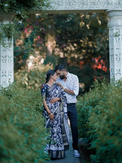 An intimate moment captured in a lush green pathway. The bride's floral print saree looks beautiful in this natural garden setting.