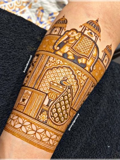 A detailed view of a bridal arm piece. This section features a royal elephant in front of a palace, with a beautiful peacock figure below it.