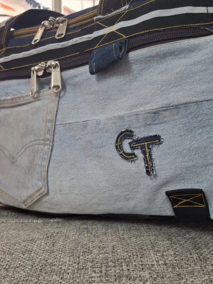 A closer look at the details of an upcycled denim duffel bag. I incorporate original jean pockets and add custom embroidery, like the 'CT' initials, to make each piece personal.