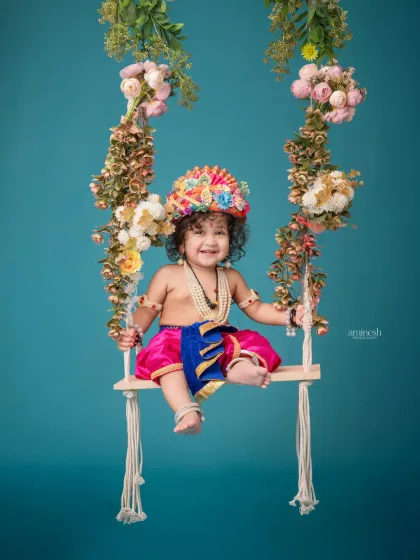 Watch your little one's joy in this playful Janmashtami setup. Dressed as baby Krishna, your child will have fun on a beautifully decorated floral swing, creating cheerful and divine portraits.