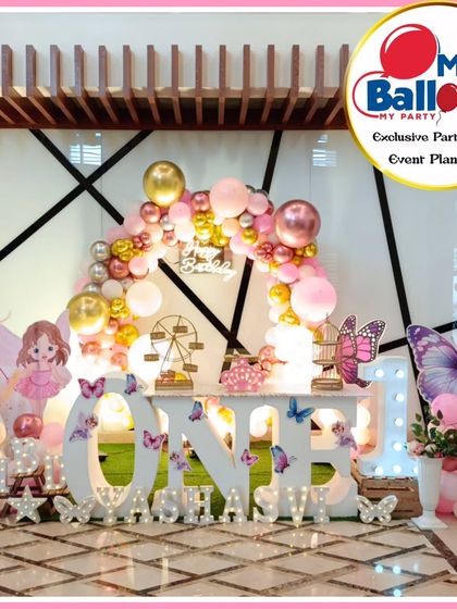A beautiful butterfly-themed first birthday. The pink and gold decor features a 'She leaves a little sparkle' backdrop, fairy cutouts, and a large light-up number '1'.