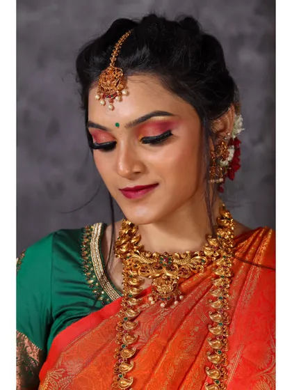 A close-up with the model's eyes gently closed, highlighting the detailed eye makeup and the texture of the silk saree.