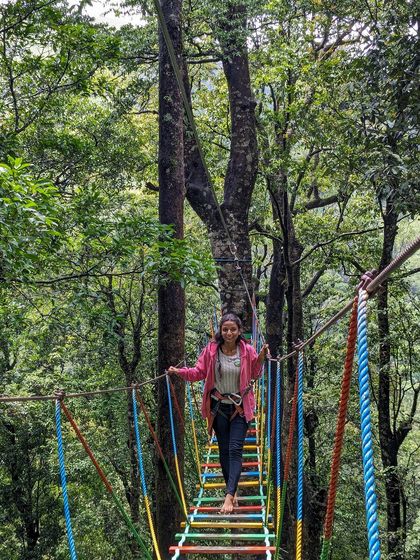 A trekker crossing a colorful rope bridge in Wayanad.